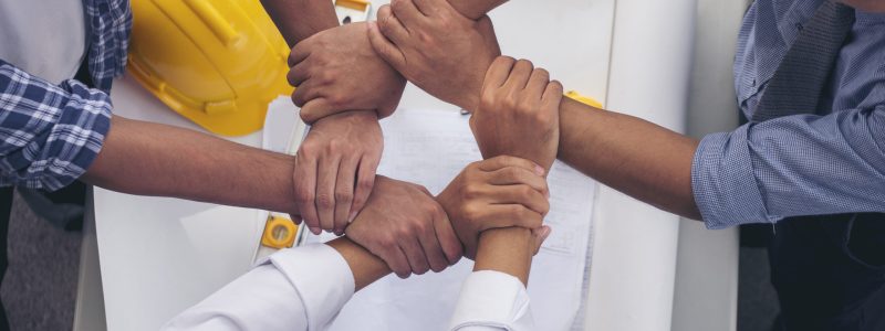 Close up engineer men hands diversity multiethnic partners team together. Group of multiracial people Engineer Manager Foreman Teamwork meeting join hands. Top view office table team join partnership